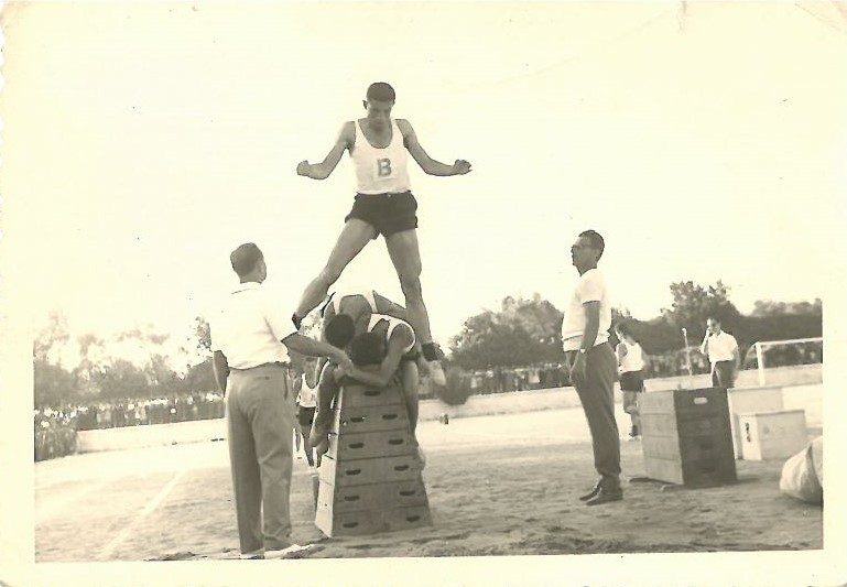 Β΄ Γυμνάσιο Άρτας (περί το 1960). Γυμναστικές επιδείξεις εφαρμοσμένο άλμα στο εφαλτήριο υπό τα βλέμματα των γυμναστών Άρη Γαλανού και Θόδωρου Μποτσώλη